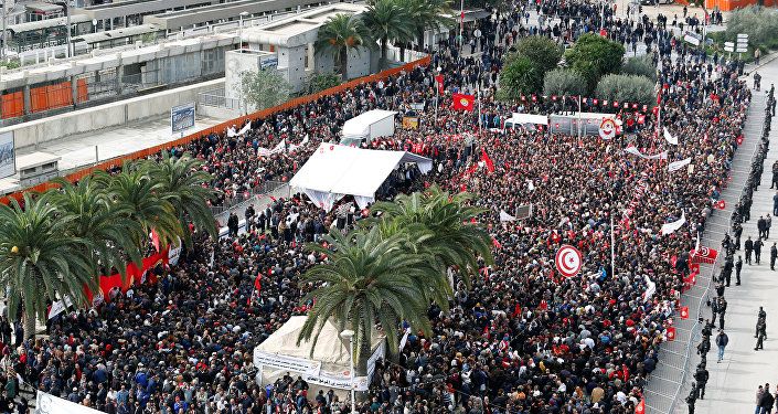 يحمل الناس أعلامًا وهم يحتجون على رفض الحكومة رفع الأجور في تونس العاصمة