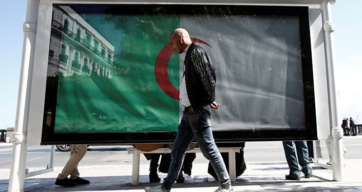 رجل يسير بجوار العلم الوطني الجزائر العاصمة