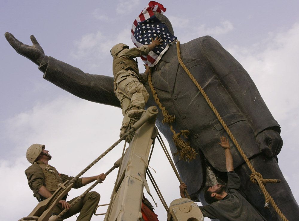 مجند أمريكي يضع علم الولايات المتحدة على رأس تمثال صدام حسين في عام 2003 في بغداد