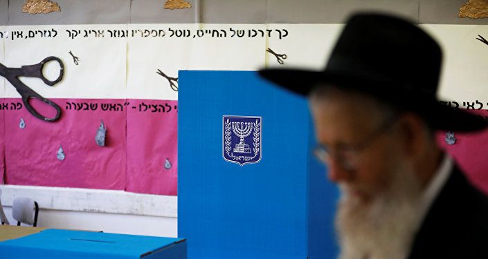 رجل يهودي متشدد يمشي بجانب كشك الاقتراع وصندوق الاقتراع في مركز اقتراع بينما يصوت الإسرائيليون في الانتخابات البرلمانية في القدس