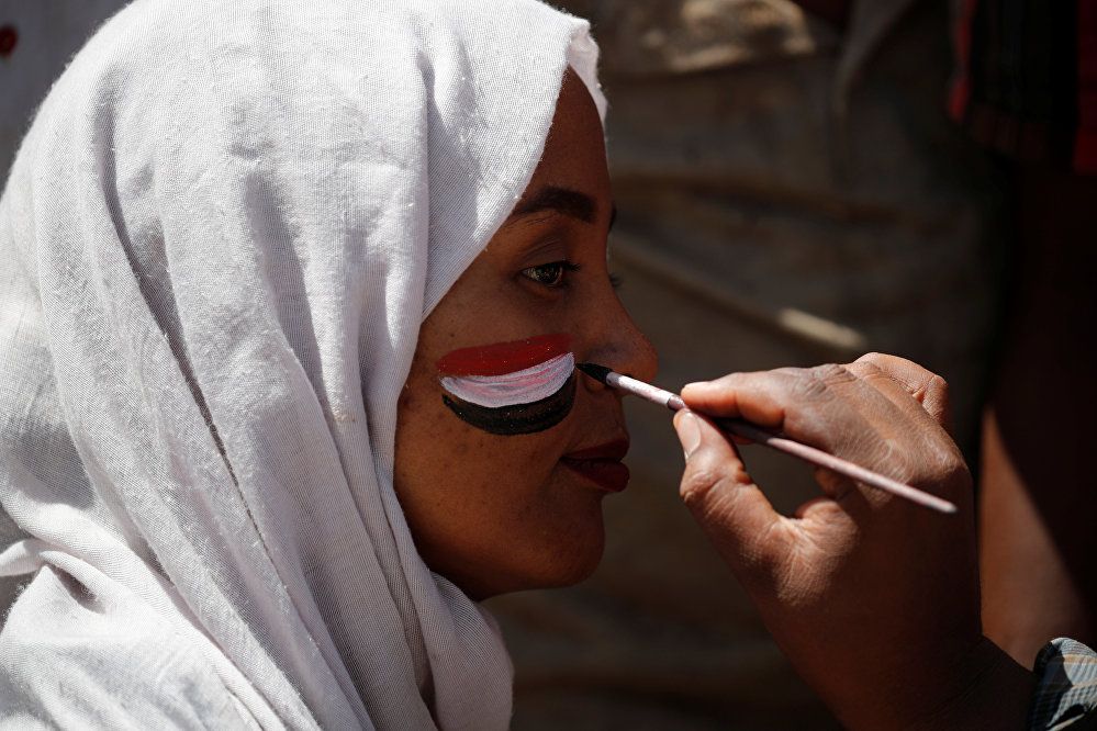 رجل يرسم العلم السوداني على وجه المتظاهرين في الخرطوم