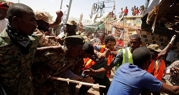 متظاهرون سودانيون يضربون رجلا يعتقد أنه عميل حكومي بينما يحاول الجنود إخراجه من الحشد في الخرطوم