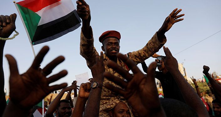 جندي سوداني يجلس على أكتاف أحد المتظاهرين وهو يهتف مع الحشد خارج وزارة الدفاع في الخرطوم