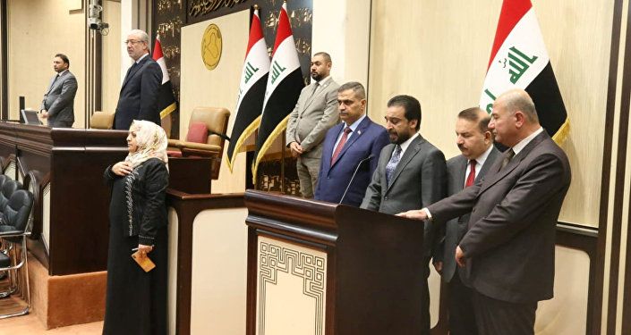رئيس البرلمان العراقي محمد الحلبوسي يقف مع الوزراء المفوضين حديثاً خلال مراسم أداء اليمين في مقر البرلمان في بغداد