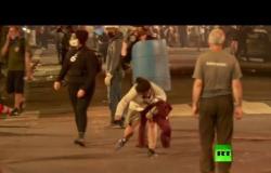 امرأة تسقط على الأرض متأثرة بالغازات التي تستخدمها شرطة بورتلاند